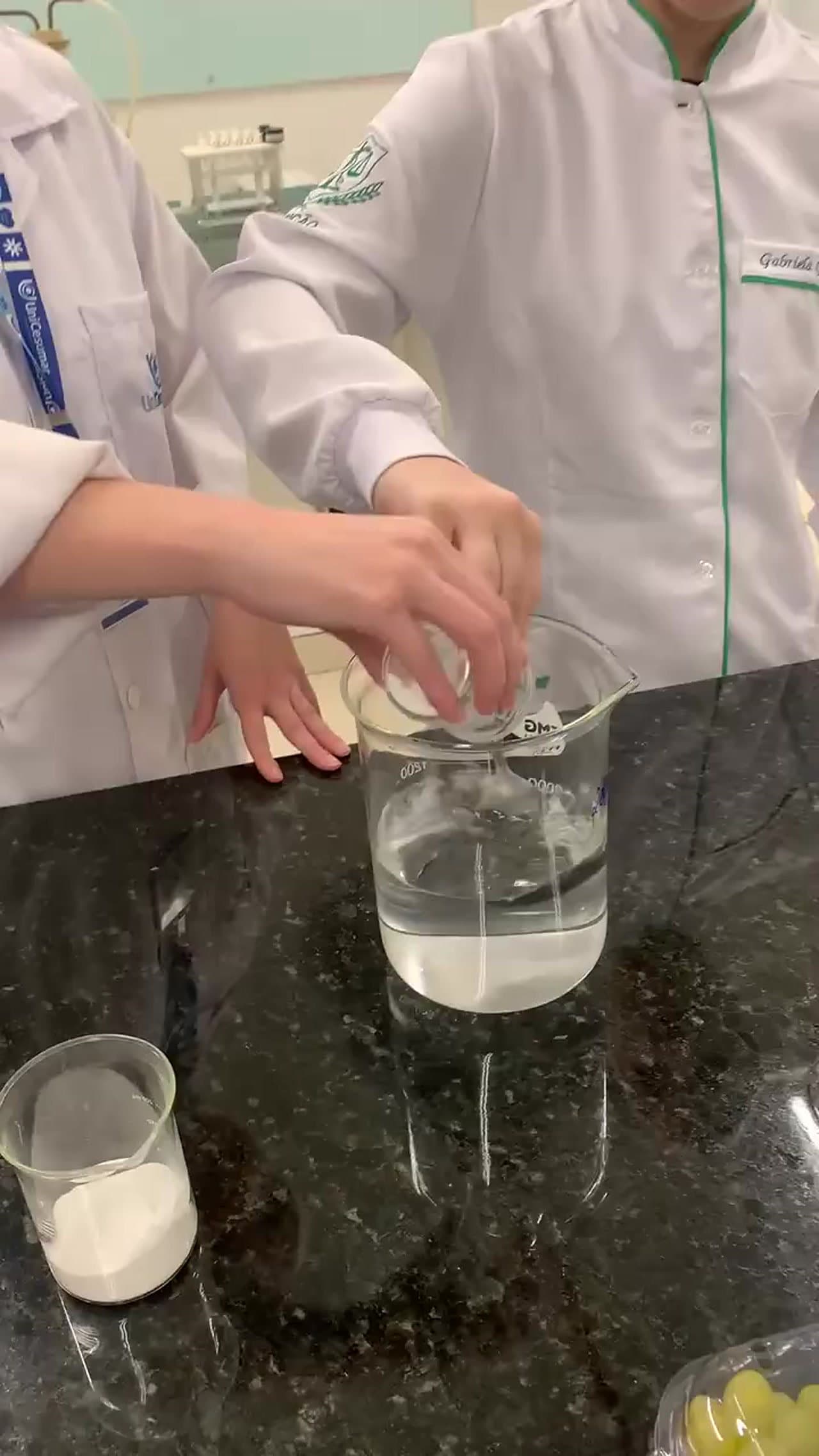 Pesquisadora de jaleco preparando a solução do revestimento em béqueres no laboratório